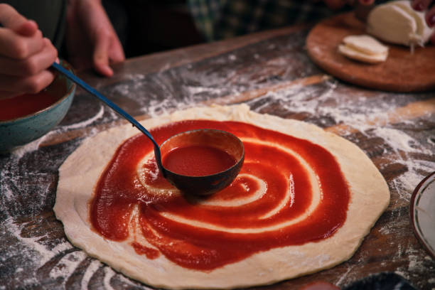 istock Preparing Pizza with Tomato Sauce, Cheese and Ham 1295819522