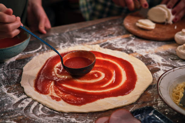 istock Preparing Pizza with Tomato Sauce, Cheese and Ham 1295821038