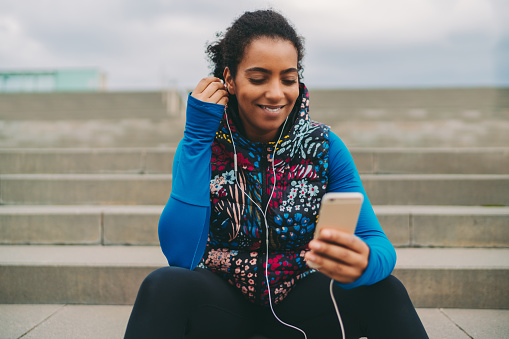 Mixed race woman using music app for sports training
