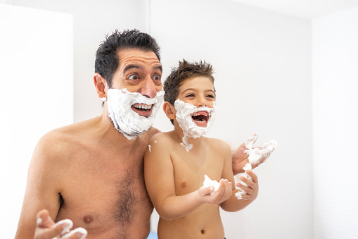Funny father and son shaving in the bathroom
