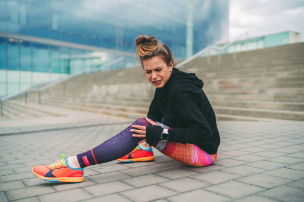 istock Sportswoman with broken leg sitting on ground 1295821894