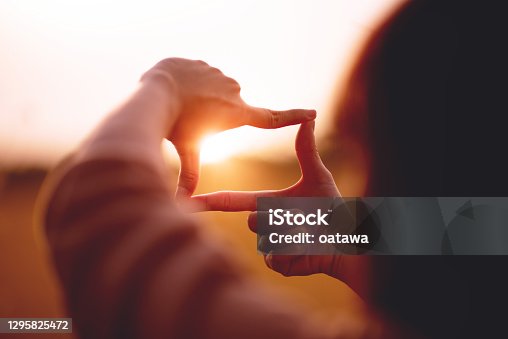 istock New year planning and vision concept, Close up of woman hands making frame gesture with sunset. 1295825472