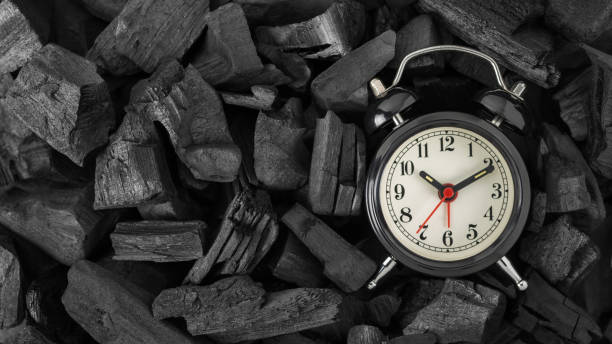 istock Black retro alarm clock on black charcoal background with copy space. Top view 1295828923