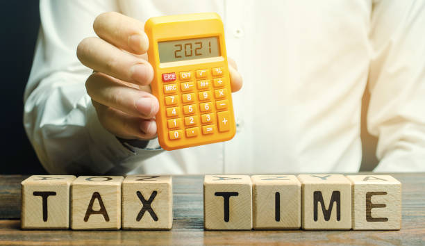 Wooden blocks with the word Tax time and taxpayer with the inscription 2021 on the calculator. The concept of paying the tax rate. Taxation, taxes burden. Pay off debts. Property income annual taxes Wooden blocks with the word Tax time and taxpayer with the inscription 2021 on the calculator. The concept of paying the tax rate. Taxation, taxes burden. Pay off debts. Property income annual taxes tax season photos stock pictures, royalty-free photos & images