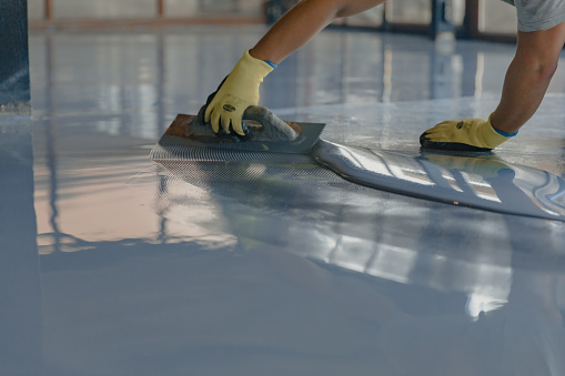 El trabajador aplica resina epoxi gris al nuevo piso photo