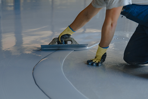 El trabajador aplica resina epoxi gris al nuevo piso photo