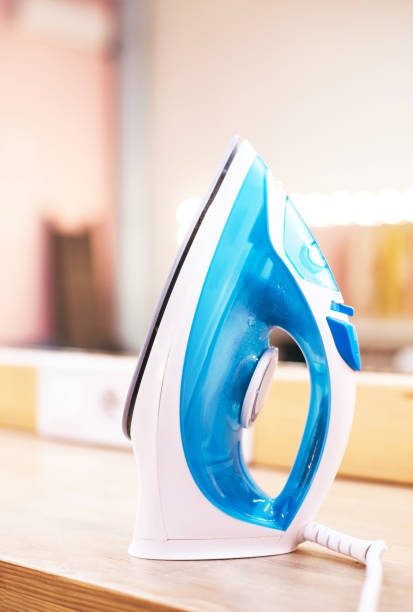 istock Modern electric steam iron on ironing board on make up room background 1295832235
