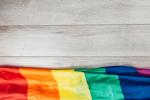 Concept of LGBTQI rainbow flag on wooden background, top view, flat lay.