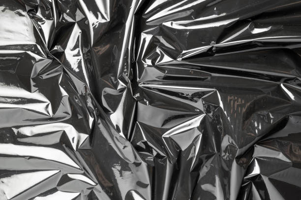 Plastic texture. Wrap transparent dark cellophane background. Black shiny film bag pattern. Real texture of polyethylene foil.