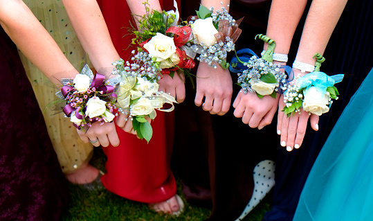 Girls holding arms out with corsage flowers for prom high school dance romance fun night party