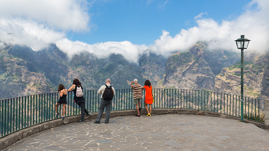 Madeira Island, Portugal - August 01, 2014: People wondering a view from high-level viewpoint at sun-drenched mountain village Curral das Freiras at Madeira Island, Portugal