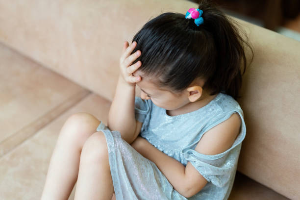 niña deprimida sentada en el sofá - displeased child abandoned child abuse fotografías e imágenes de stock