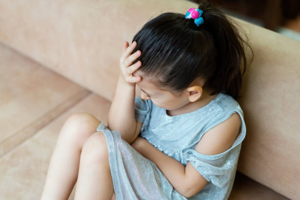 istock Depressed little girl sitting on the sofa 1295836075