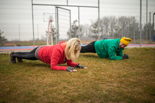Senior couple doing plank while exercising together outdoors on autumn day