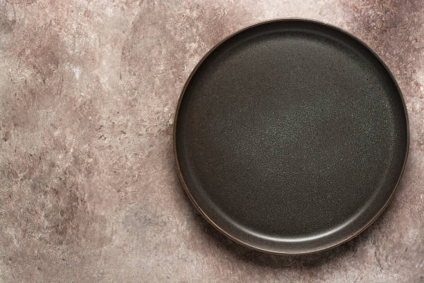 istock Empty craft plate in gray-brown on beige grunge background. Top view, flat lay. 1295838043