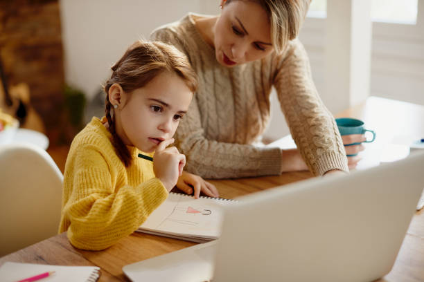 istock Small girl e-learning with help of her mother at home. 1295838668