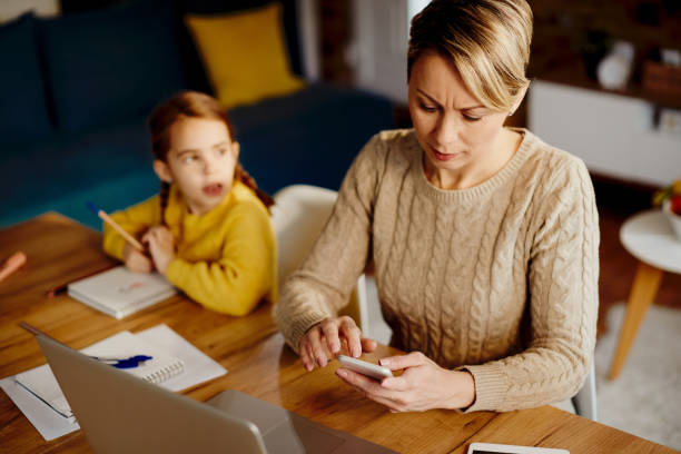 istock Mid adult mother using smart phone while working at home. 1295838939