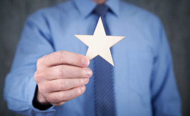 istock Man holding wooden star. Rating 1295839338