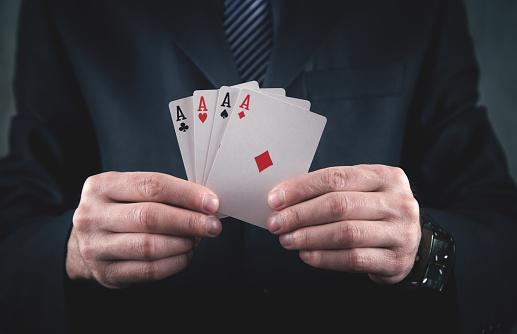 Businessman in suit holding playing cards.