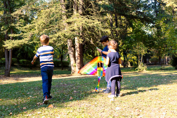 istock Group of kids playing with a kite at the park. 1295843018