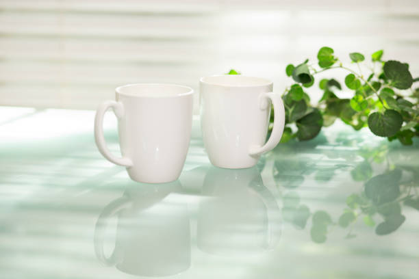 istock A pair of coffee mugs sit on glass top table. 1295845090