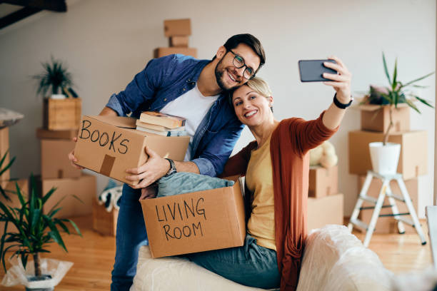 istock Happy couple taking selfie with smart phone while moving into new home. 1295845138