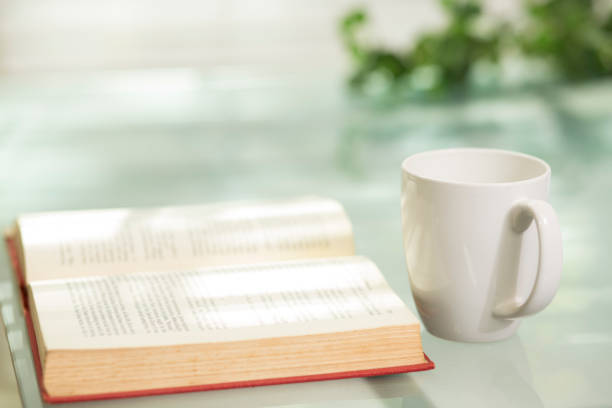 istock A single coffee mug sit on glass top table near an open book.. 1295845174