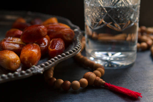 istock Iftar evening meal, beads, dates and a glass of water on a dark backdrop, with a copy space 1295845943
