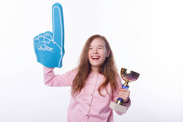 若い幸せな小さな女の子は、ファングローブを着用し、勝者のトロフィーを保持しています。 - business team corporate business business person ストックフォトと画像