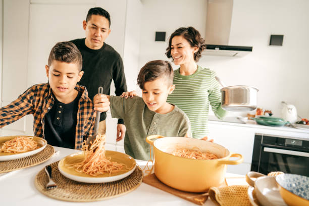 Family Mortgage Planners Healthy lifestyle for the family. Serving pasta for lunch kids eating noodles stock pictures, royalty-free photos & images