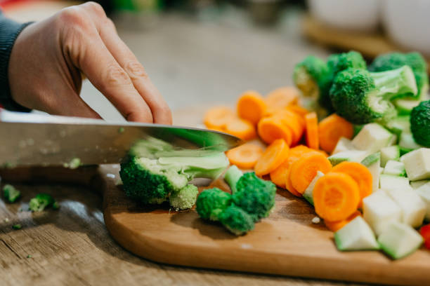 istock Hand holding knife and cutting veggies 1295846291