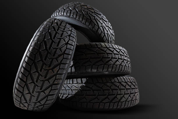 istock Stack of four new black tyres for winter car on black background 1295846449