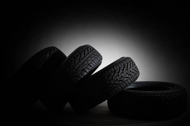 istock Stack of four new black tyres for winter car on black background 1295846454