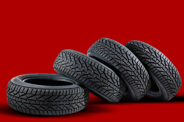 istock Stack of four new red tyres for winter car on blue background 1295846503