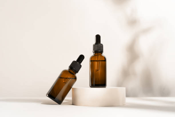 istock Glass dropper bottles on the white marble background. 1295847256