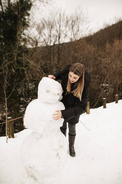 istock Young woman making a snowman 1295847356
