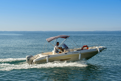 Lake Garda, Italy - September 2018:  Person driving a small motor boat on Lake Garda.