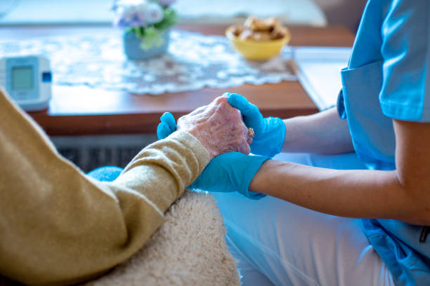 Comforting hands. Close-up. Surgical gloves. Young female doctor is holding her patient's hand, comforting her. Old lady is worried and doctor is there to take care of her every need. Old lady is in trusting hands. social services stock pictures, royalty-free photos & images