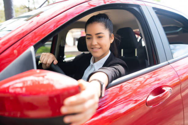 istock Woman moving rear view wing mirror in car. 1295851505