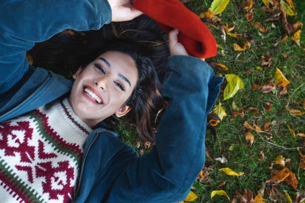 istock smiling young woman lying down on the grass 1295853551