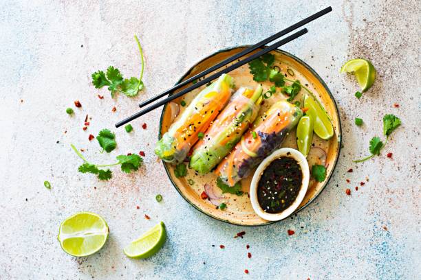 istock Fresh Asian appetizer Spring rolls (Nem) made from rice paper and raw vegetables and herbs with hot sauce on a light blue background. Vietnamese Food 1295854685