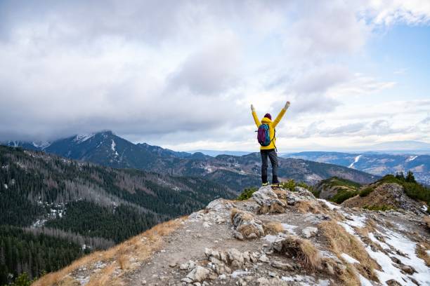 istock Hiker woman in yellow down jacket on the mountain ridge. 1295854764