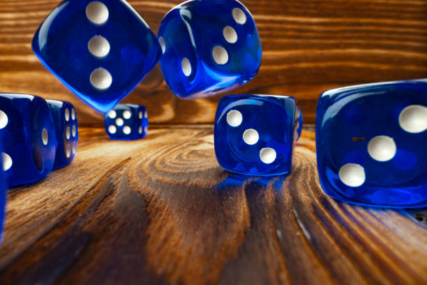 istock Blue dice cubes against brown wooden background close up 1295855190