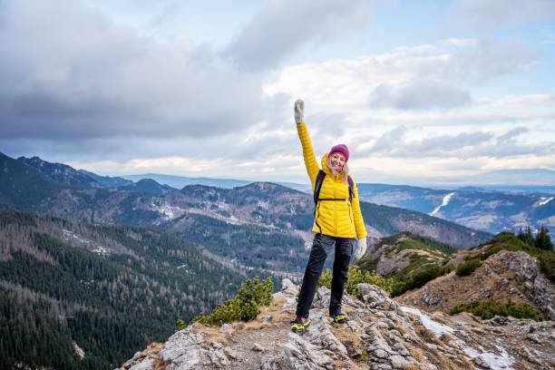 istock Hiker woman standing with hands up achieving the top. 1295855394