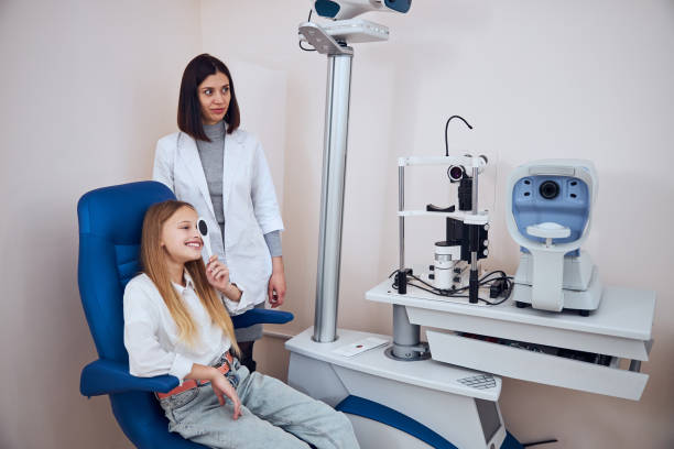 istock Seriously brunette doctor checking child vision and looking for problems and caring for eyes 1295856325