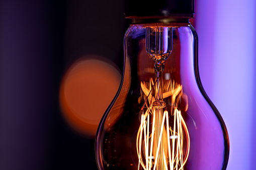 A burning lamp hangs in the dark on a blurred background. The concept of decor and atmosphere.