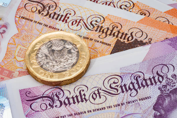 монета номиналом один фунт помещена на банкноту - one pound coin british currency coin paper currency стоковые фото и изображения