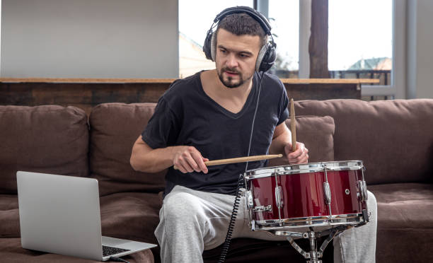 istock A young man with headphones learns to play the drum using online lessons. 1295858506