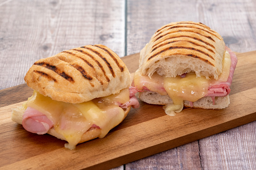 Cheese and ham toasted panini melt on a wooden board