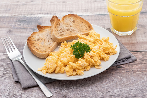 Breakfast of scrambled eggs with toasted bread and orange juice